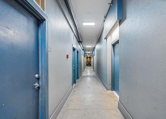 A long hallway with blue doors and white walls.