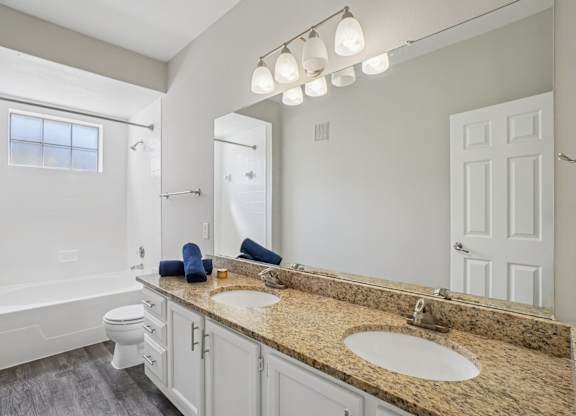 A bathroom with a granite countertop and white fixtures.