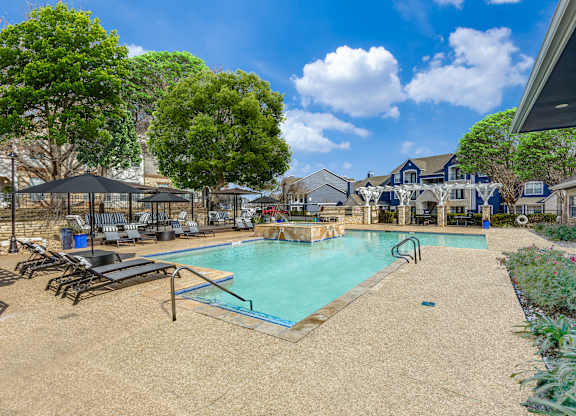 A pool surrounded by trees and a building in the background.
