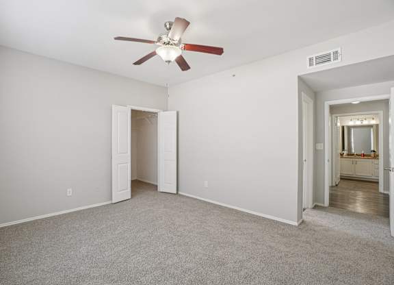 A room with a ceiling fan and carpeted floor.