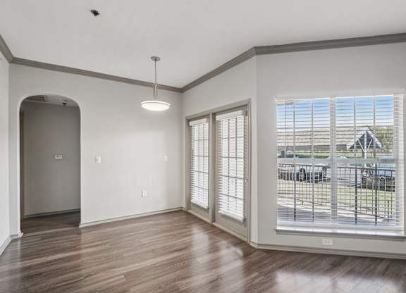 A room with a wooden floor and a large window with blinds.