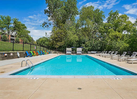 A large outdoor swimming pool surrounded by trees and lounge chairs.