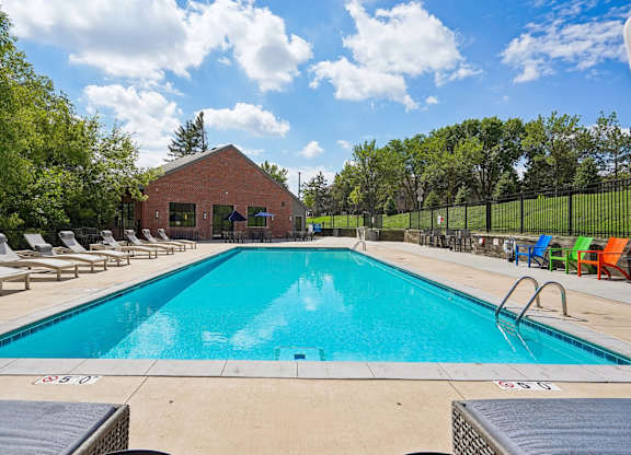 A large swimming pool surrounded by lounge chairs and trees.