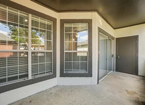 A concrete balcony with a sliding door and windows.