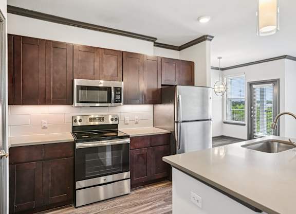 A modern kitchen with dark brown cabinets and stainless steel appliances.