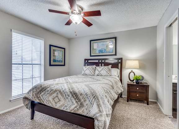 A bedroom with a bed, nightstand, and two pictures on the wall.