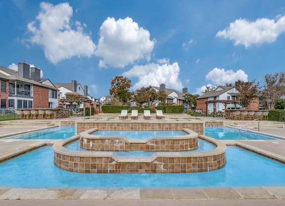 A large outdoor swimming pool with a hot tub in the middle.