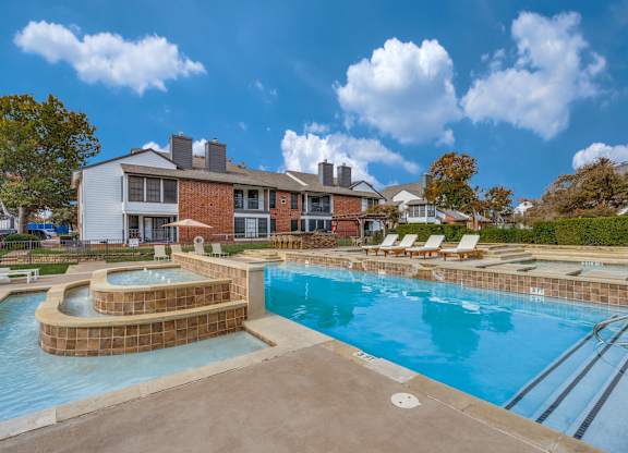 A large swimming pool with a small wading pool in front of a residential building.