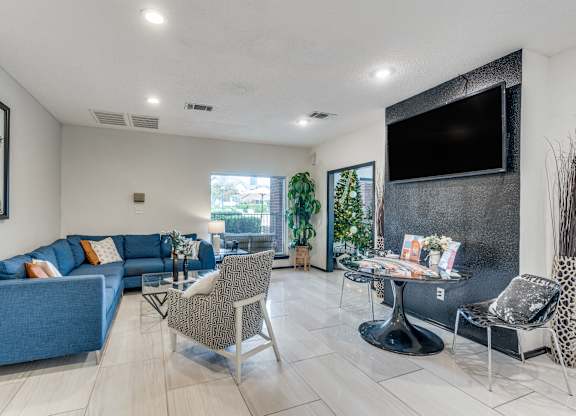 A living room with a blue couch and a television on the wall.