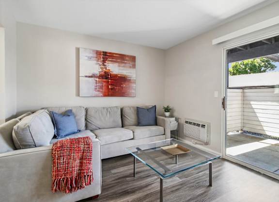 A living room with a grey couch and a red throw.
