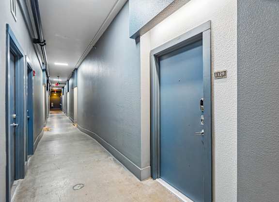 A long hallway with doors on both sides and a sign on the wall.
