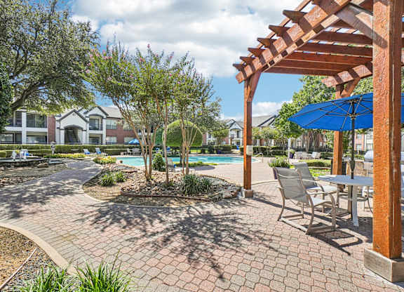 A patio with a table and chairs under a pergola.