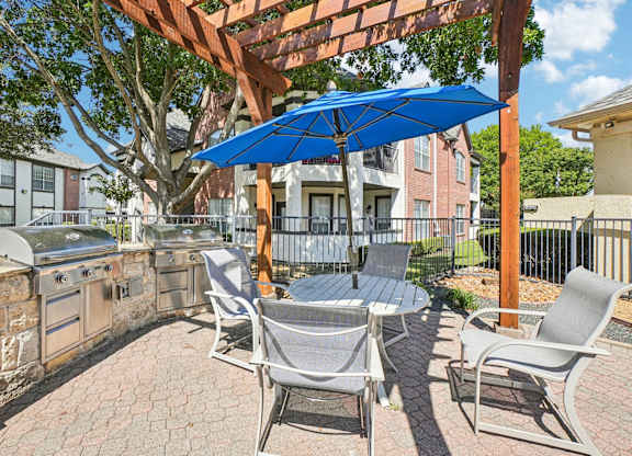 A patio with a table and chairs under a blue umbrella.