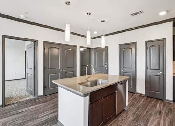 A modern kitchen with a central island and dark wood floors.