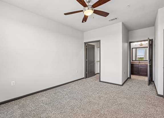 A room with a ceiling fan and carpeted floor.