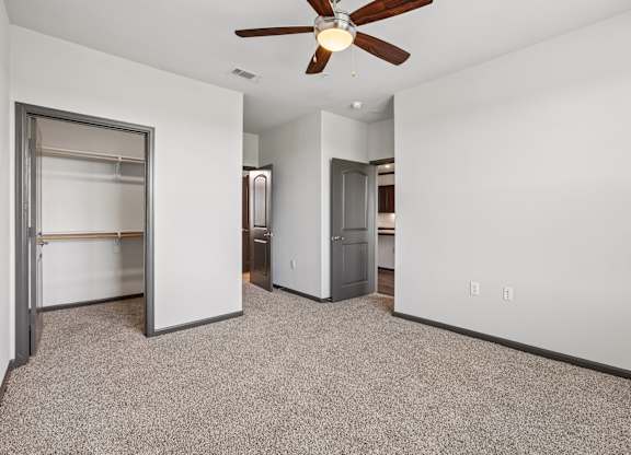A room with a ceiling fan and a white wall.