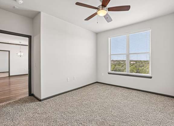 A room with a ceiling fan and a window with blinds.