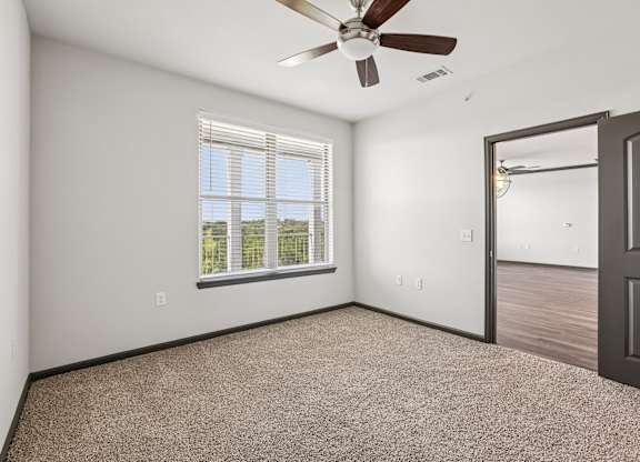 A room with a ceiling fan and a window with blinds.