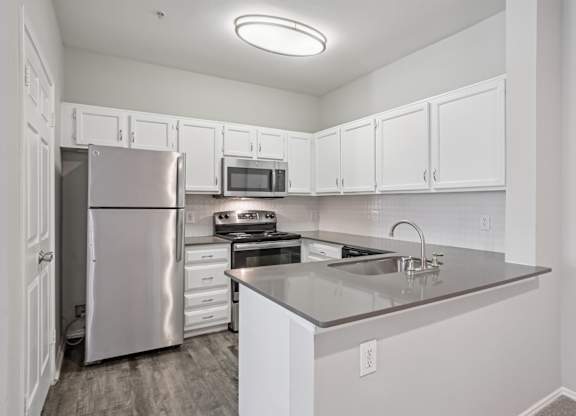 A kitchen with white cabinets and a stainless steel refrigerator.