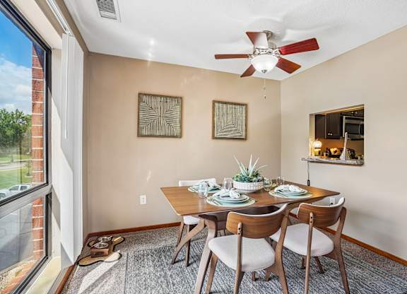 A dining room with a table set for two and a ceiling fan.