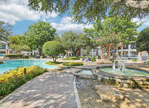 A beautiful outdoor scene with a fountain, trees, and a swimming pool.