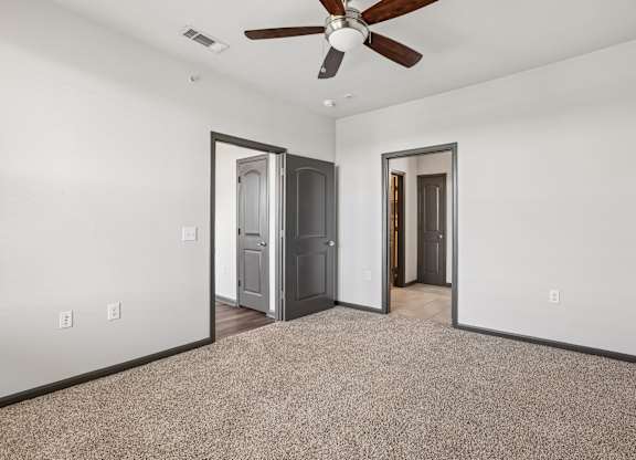 A room with a ceiling fan and two doors.