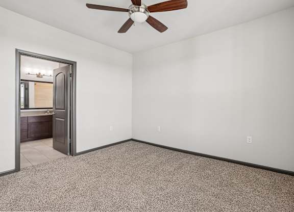 A room with a ceiling fan and a door leading to another room.
