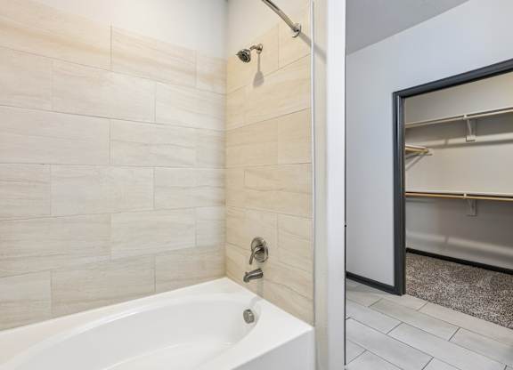 A white bathtub in a bathroom with a tile wall.