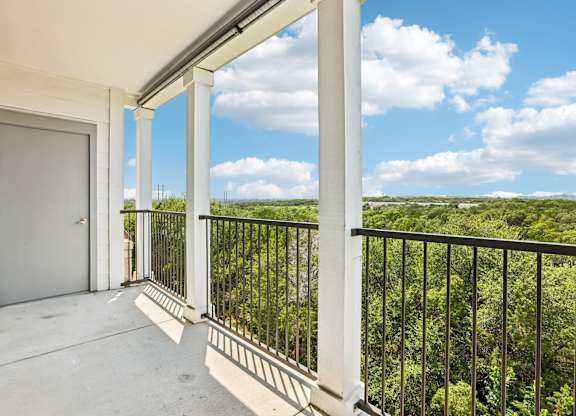A balcony with a view of a green landscape.