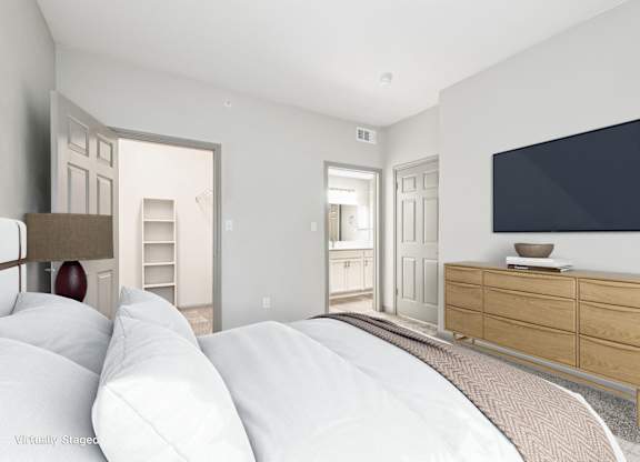 A bedroom with a large bed and a flat screen TV mounted on the wall.