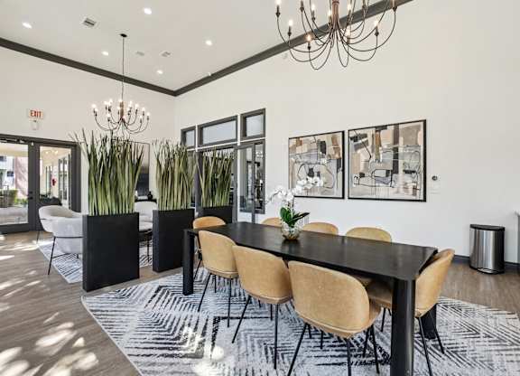 A black dining table with six chairs and a chandelier hangs above it.