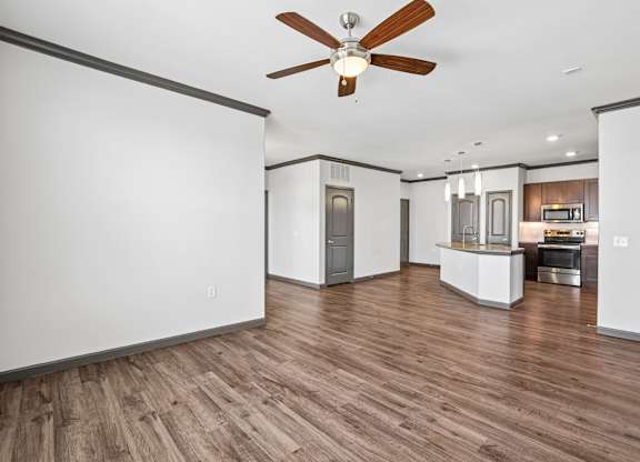 A room with a ceiling fan and wooden flooring.