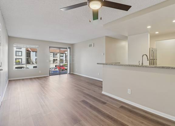 A spacious room with a ceiling fan and wooden flooring.