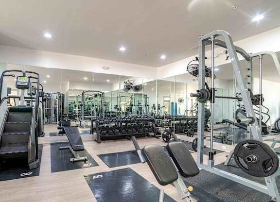A spacious gym with a variety of equipment including treadmills, weight benches, and dumbbells.