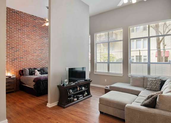 Atlanta, GA Apartments - Biltmore at Midtown - Living Room Area with wood style flooring and exposed brick wall