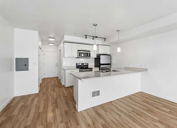 A kitchen with white cabinets and a wooden floor.