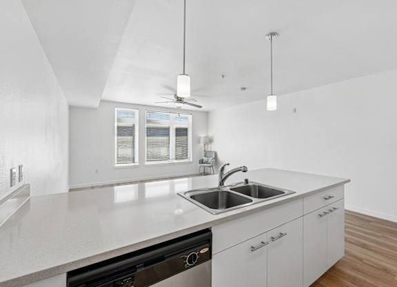 A modern kitchen with a stainless steel sink and white cabinets.