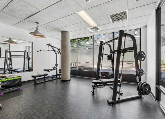 A gym with a variety of equipment including a squat rack, bench, and weights.