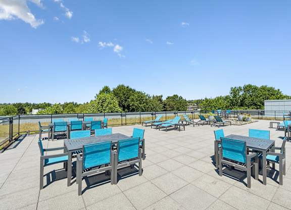 A patio with blue chairs and tables is set up for outdoor dining.