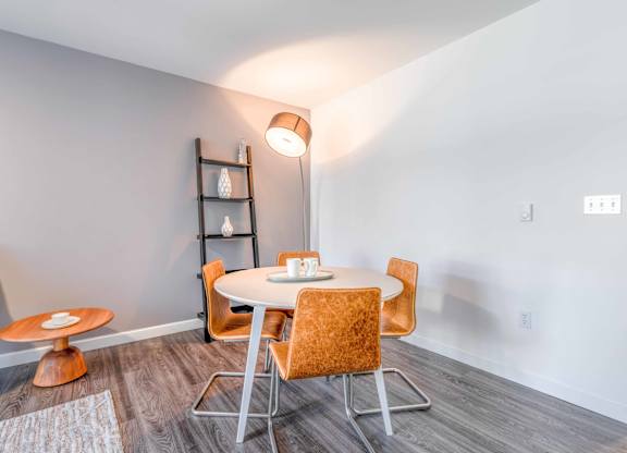 a dining area with a round table and orange chairs