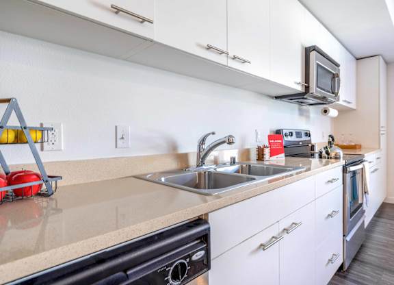 One Bedroom Apartments in Green Lake Seattle WA - Circa Green Lake - Kitchen with White Cabinets, Beige Countertops, and Stainless Steel Appliances.