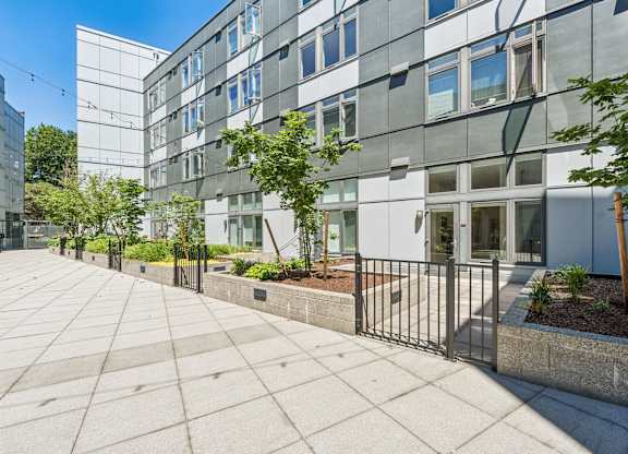 A modern building with a glass facade and a metal fence in front.