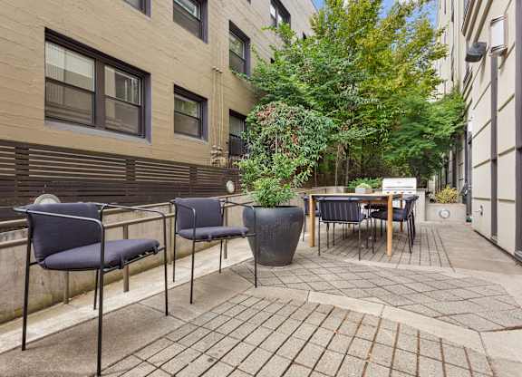 a patio with chairs and a table and a tree