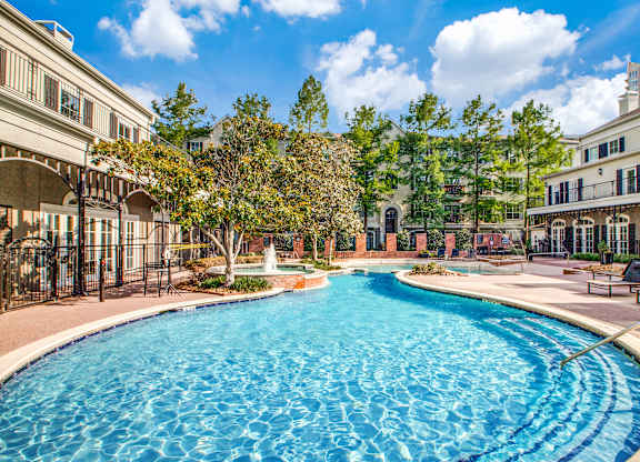 Washington Avenue Coalition, TX, Luxury Apartments Near Upper Kirby - Marcella Memorial Heights - A Swimming Pool Surrounded By Elegant Buildings, Lush Landscaping, And Sun Loungers.