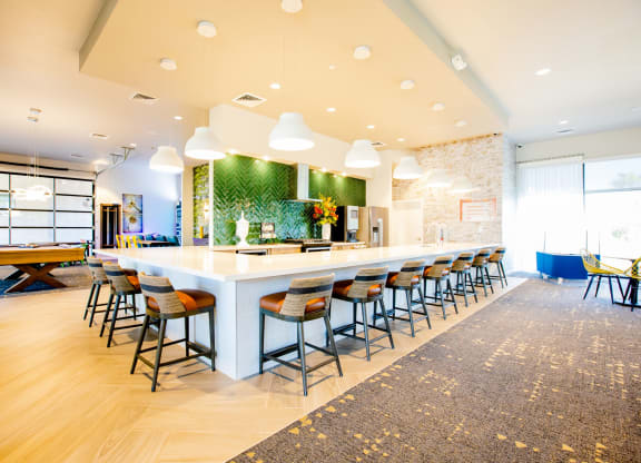 a long bar with chairs and a table in a lobby