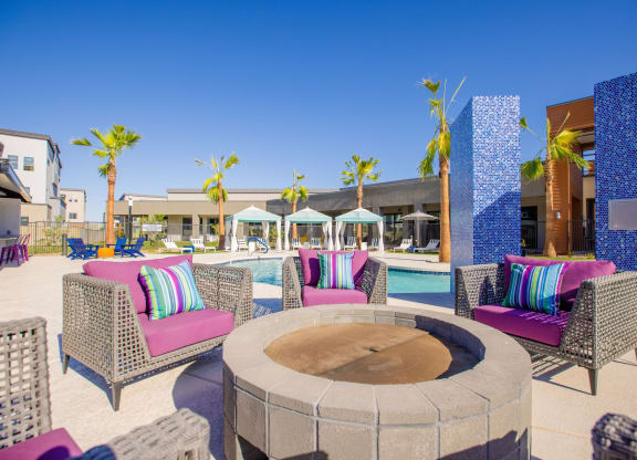 a patio with a fire pit and chairs and a pool