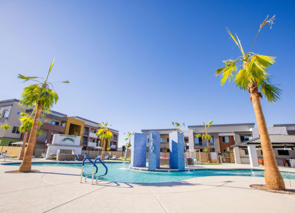 a swimming pool with palm trees and apartments in the background