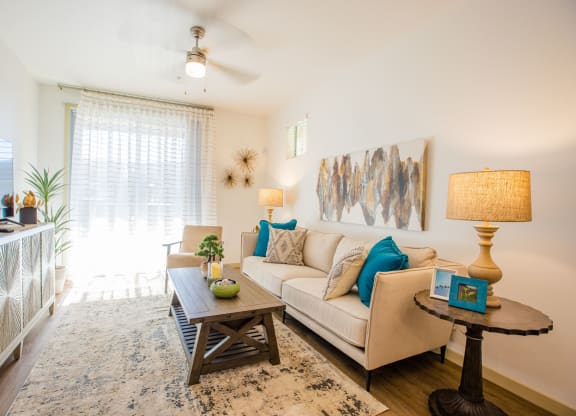 Apartments in Gilbert, AZ for Rent - Curve At Gilbert - Living Room With A Ceiling Fan, Plank Flooring, And A Sliding Glass Door To A Private Patio/Balcony