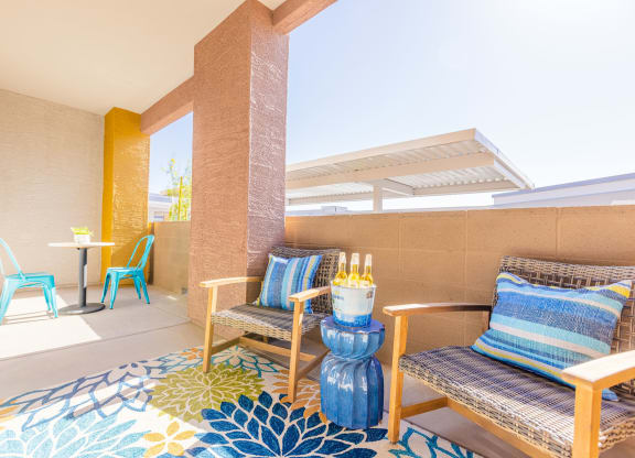 a patio with two chairs and a table and a large rug