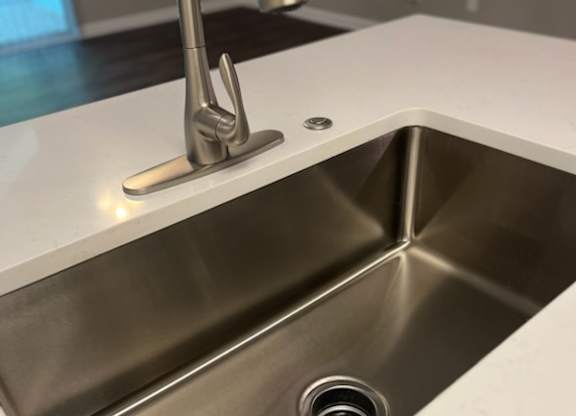 a stainless steel sink with a tap in a kitchen